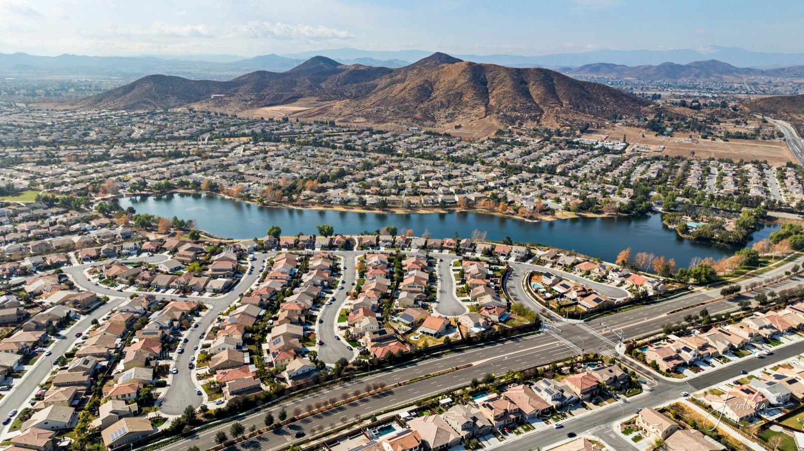 Homes wrapping around the lake at Heritage Lake in Menifee with the hills behind