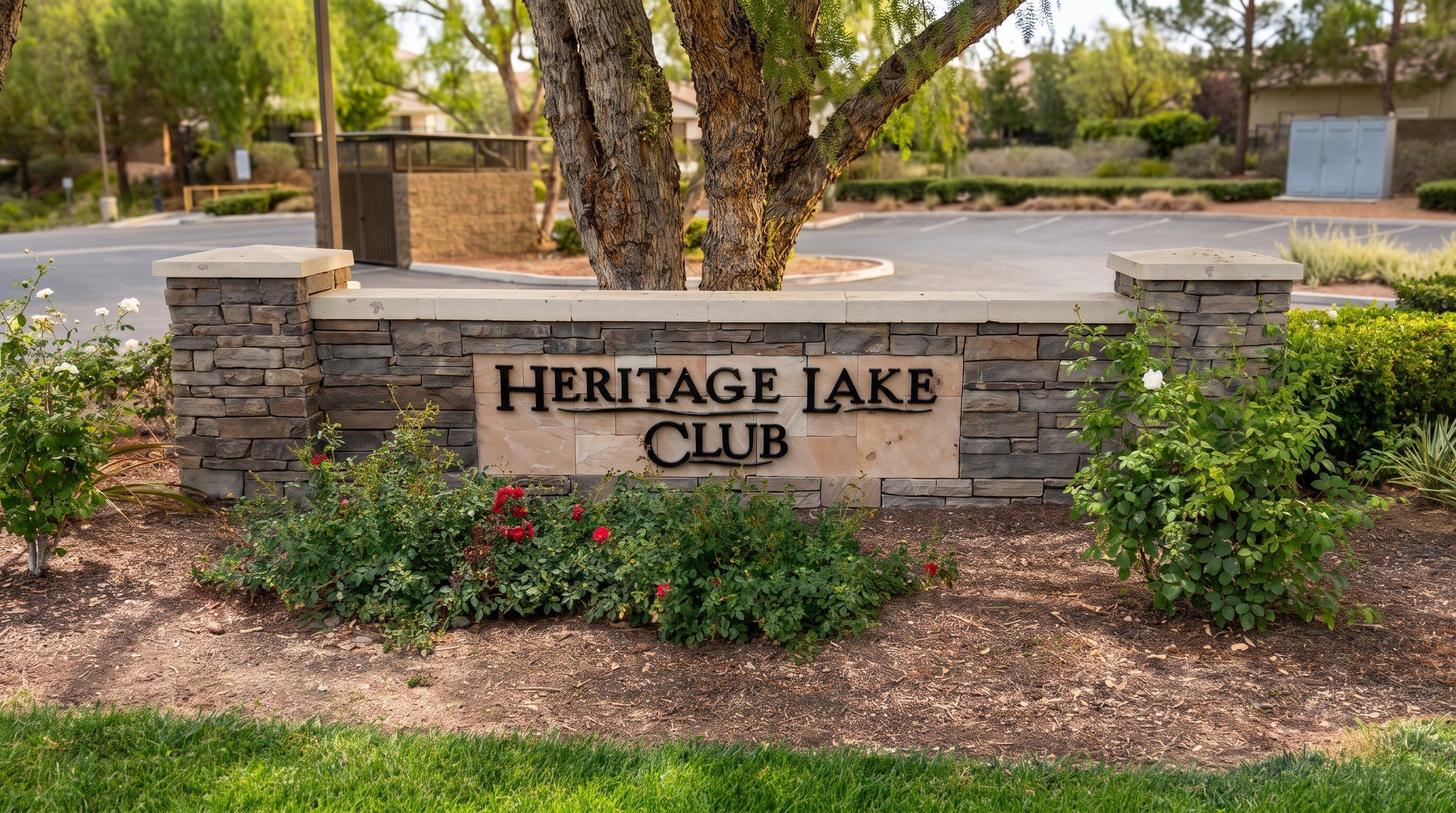 The stone Heritage Lake Club sign surrounded by flowers and shade trees