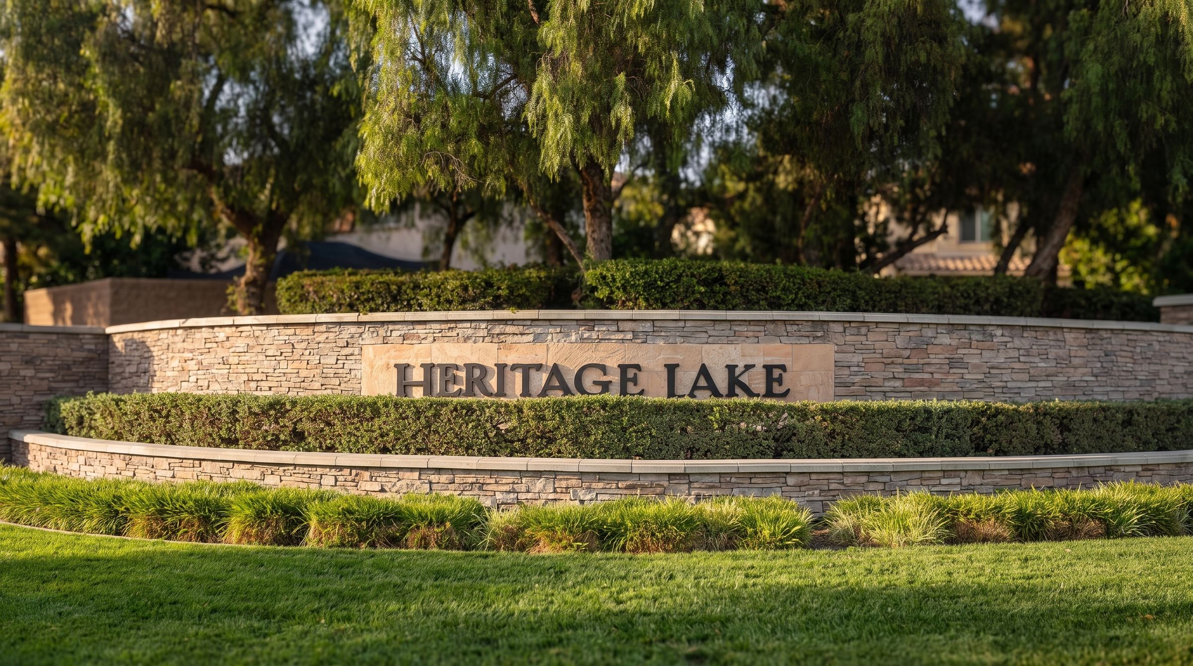 The stone Heritage Lake entrance sign framed by green lawn and mature trees in Menifee