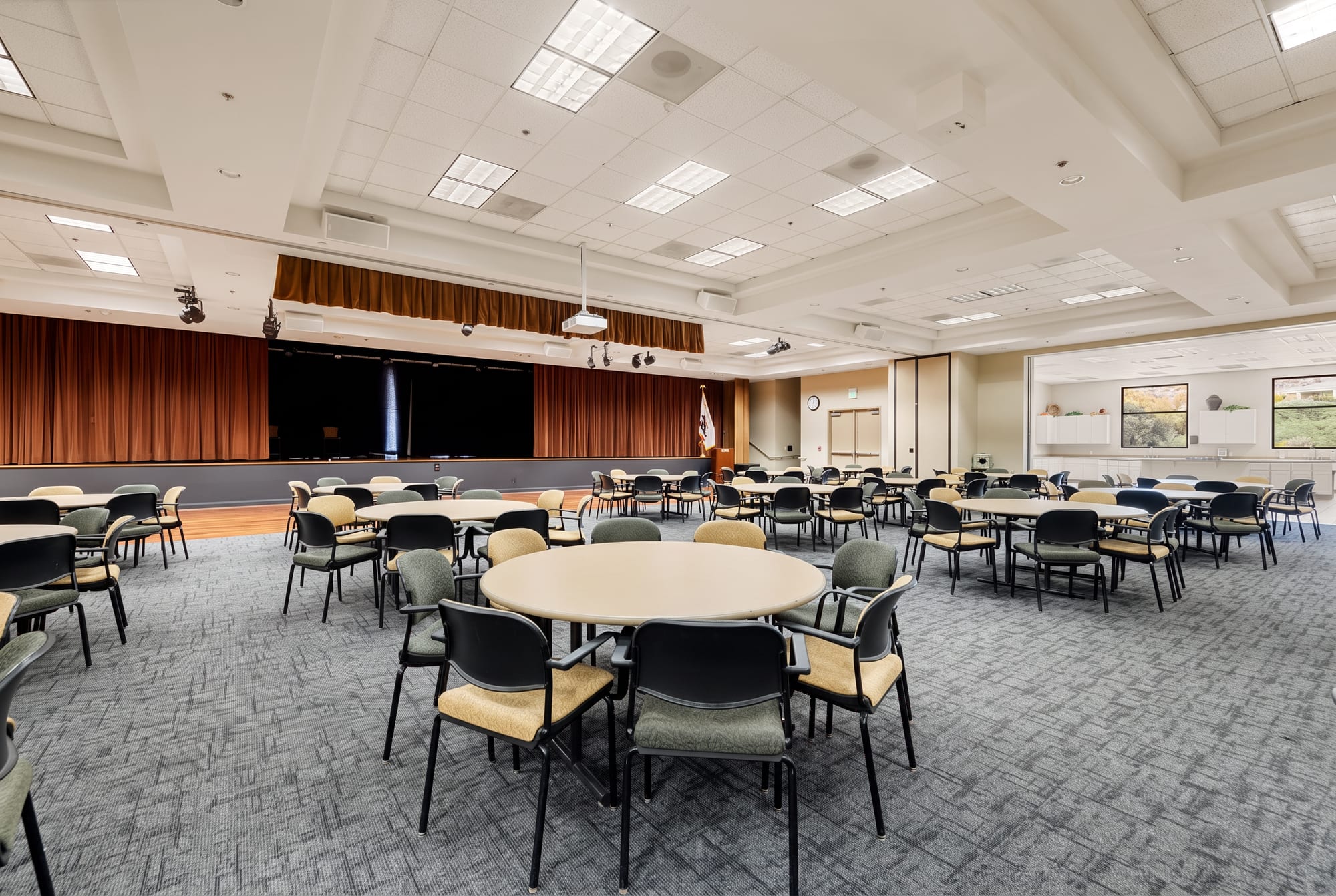 The ballroom at The Oasis clubhouse in Menifee, set with round tables in front of a stage