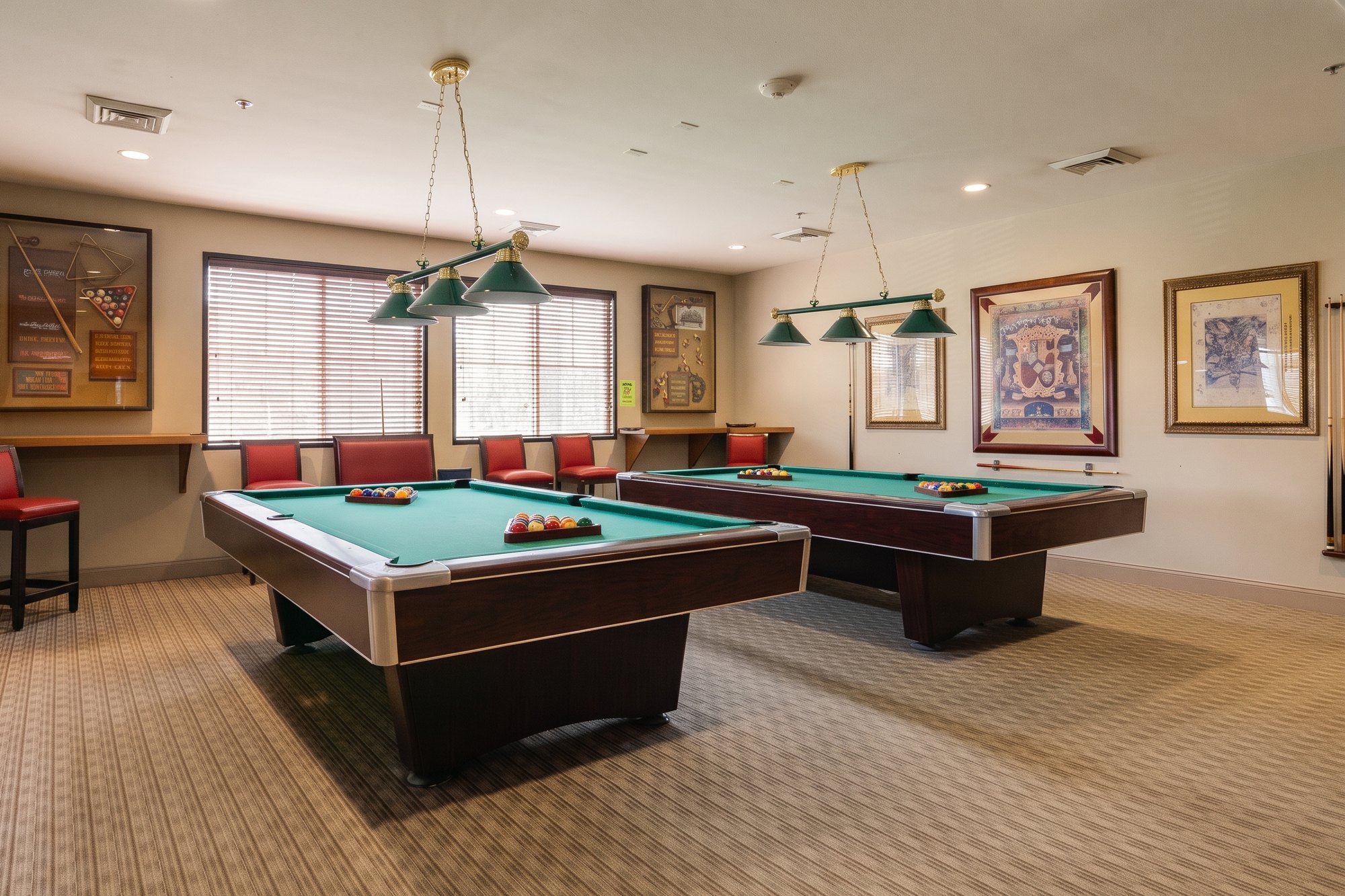 Two pool tables under green pendant lights in the billiards room at The Oasis clubhouse in Menifee