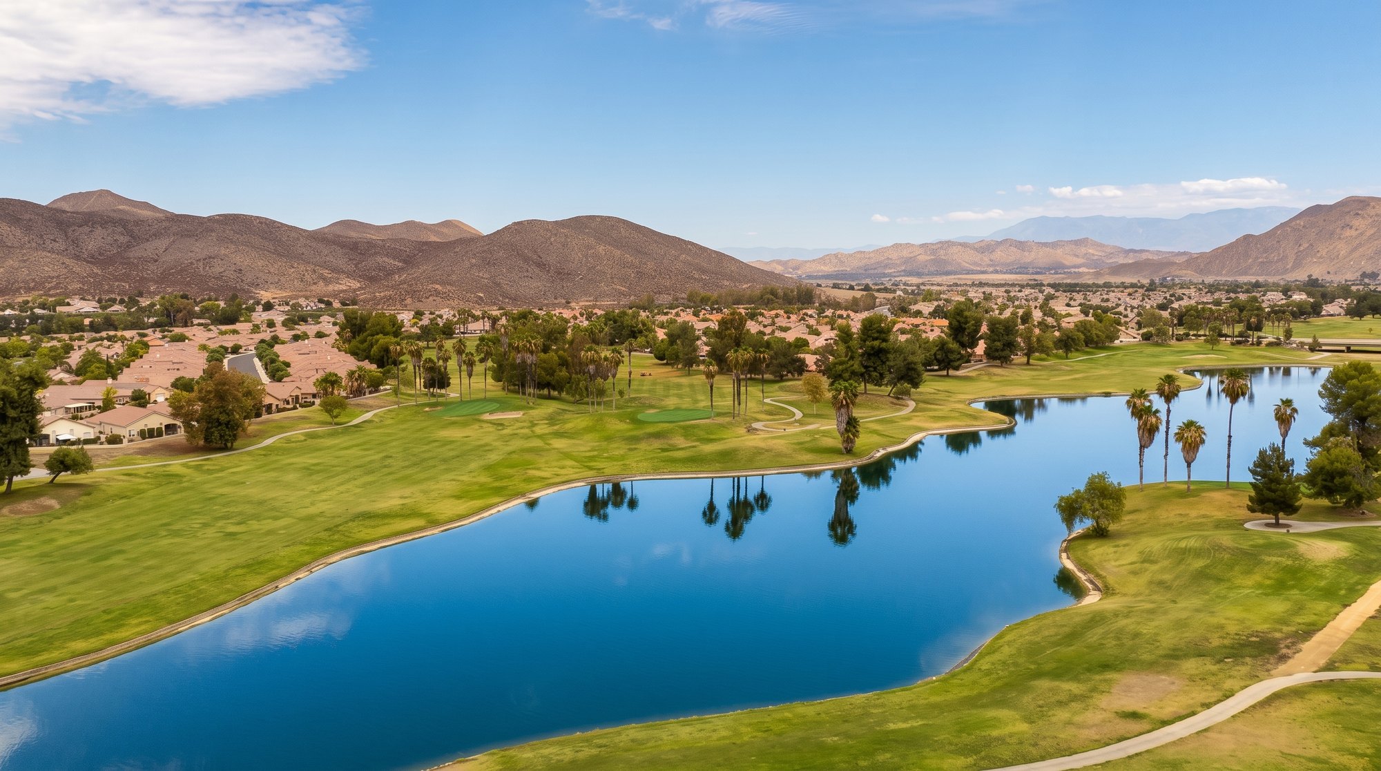 A calm lake beside the fairway at Menifee Lakes Country Club, next to The Oasis in Menifee, with the hills behind