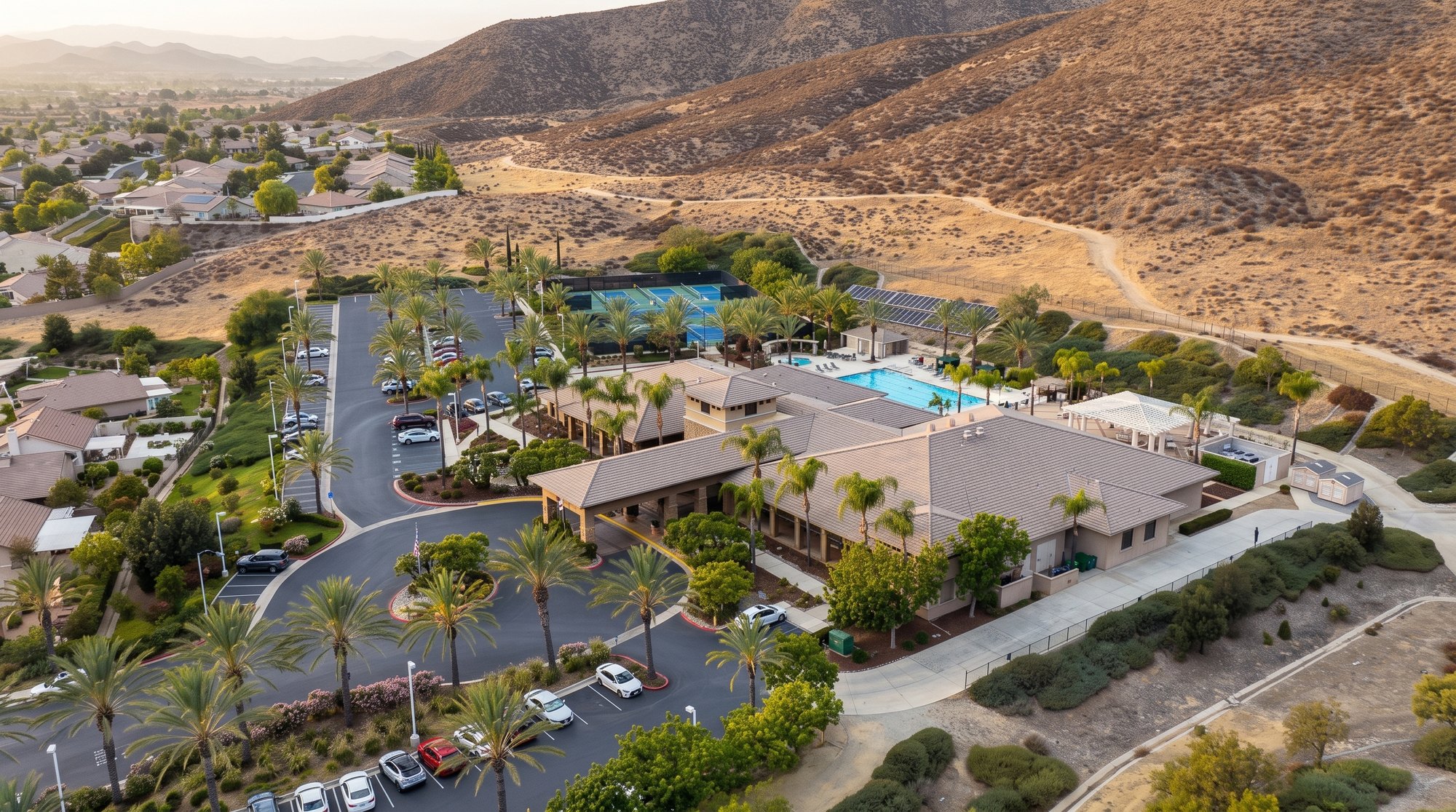 Aerial view of The Oasis recreation center in Menifee with its pool, tennis courts and palm lined drive against the hills